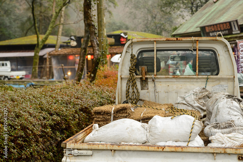 Close-up detail of a miniature pickup truck filled with stacks of hay and sacks of fertilizer parked at a rural Japanese village. Takachiho, Miyazaki, Japan. Travel and agriculture lifestyle concept. photo