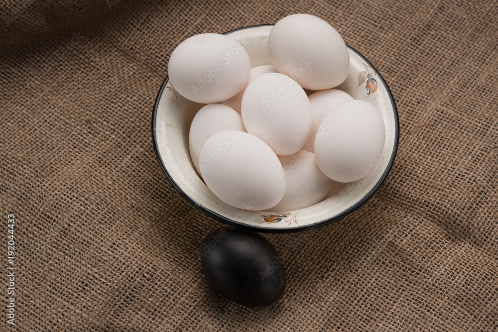 Eggs in a bowl on cloth and one black Eggs in a bowl on cloth and one black