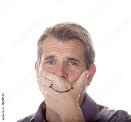 Man hiding his true emotions by covering his mouth with a fake smile drawn on his hand.