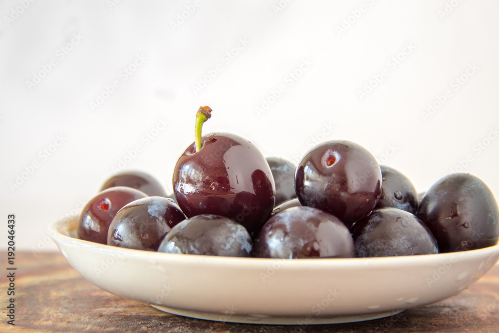 Fresh plums in plate with waterdrops on white background Fresh plums in plate with waterdrops on white background