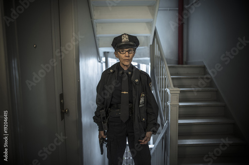 Portrait of older Caucasian policewoman holding gun in apartment staircase photo