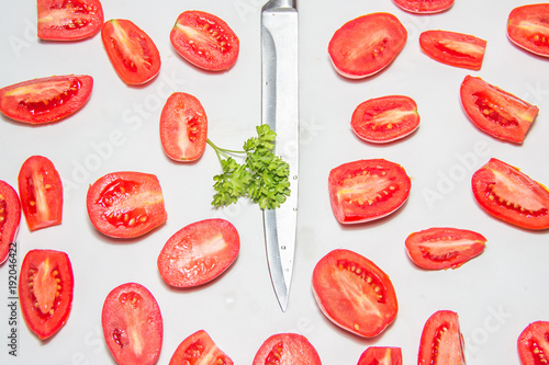Slices of red ripe tomato on a white background on the kitchen. Tomato divided in half, steal knife and fresh herbs on the center. Healthy food pattern collage