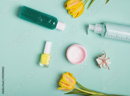 Bottles with feminine body care producs and yellow tulips on the bright background photo