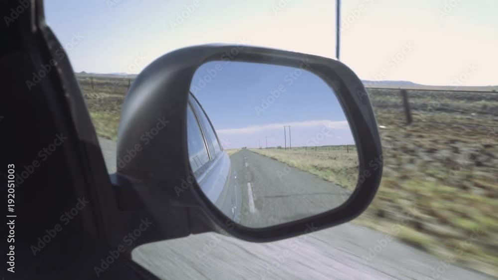 Driving along deserted country road viewed from side view mirror. Driving along deserted country road viewed from side view mirror.