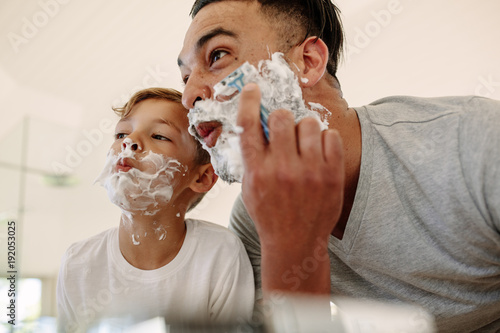 Funny father and son shaving in bathroom