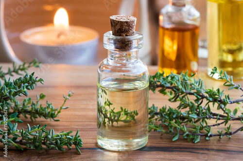 A transparent bottle of thyme essential oil with fresh thyme twigs