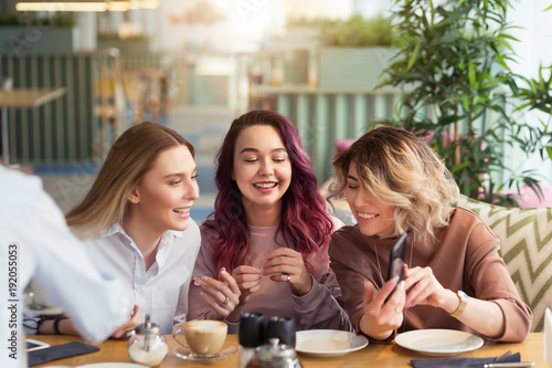 Gossipgirls, freindship concept. Female friends with tea and coffee speaking in cafe, gossip and news. Smiling women laughing, talking and smiling together in coffee shop