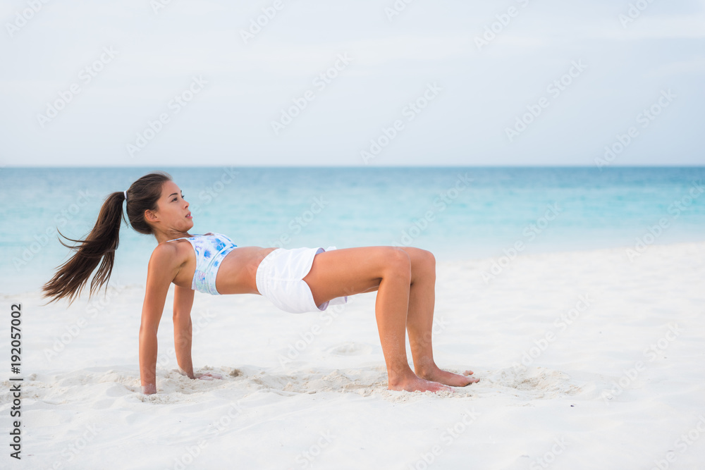 Reverse table top pose in Yoga. Advanced fitness training exercise workout girl on beach exercising core and arm muscles, posture that stretches the front body. Asian woman outside.