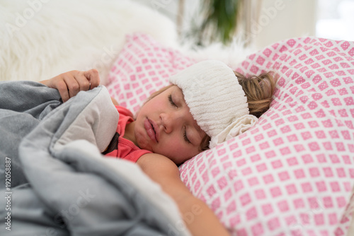 Young girl lying ill in bed at home.