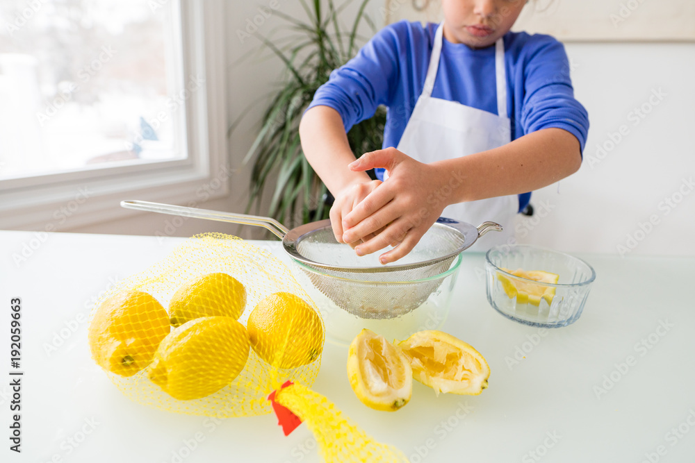 Young girl squeezing lemons into bowl. Young girl squeezing lemons into bowl.