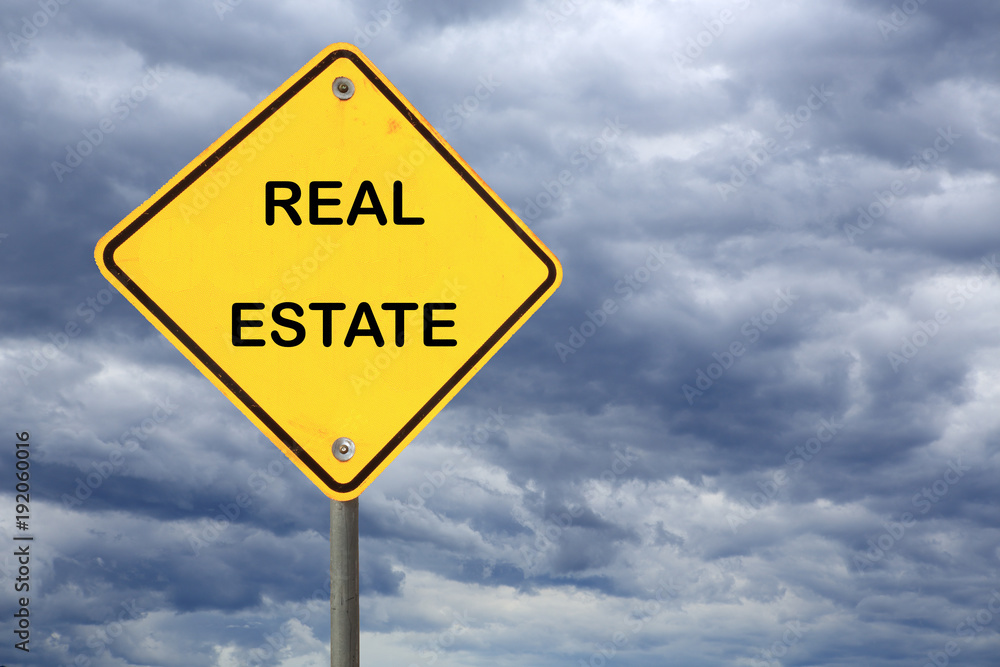 yellow road sign with text real estate against stormy sky yellow road sign with text real estate against stormy sky