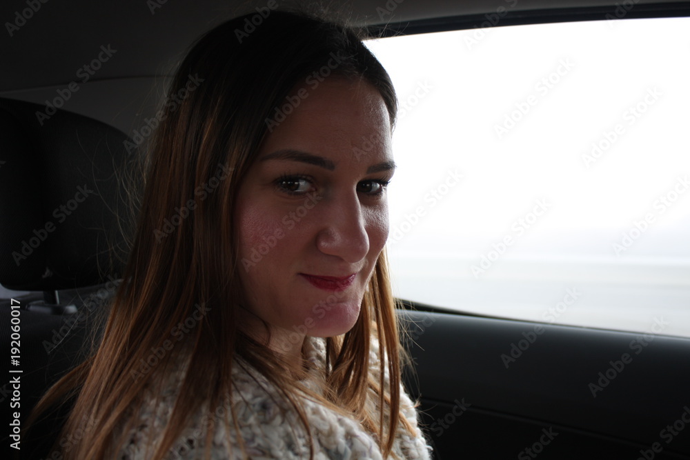 Smiling young woman sitting in land vehicle on back seat Smiling young woman sitting in land vehicle on back seat