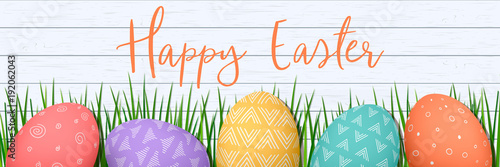 Happy Easter. Easter colorful eggs in row on white wooden wooden Scandinavian background with herbs