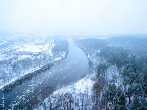 It is snowing in Vilnius, Lithuania, aerial top view of Neris river in winter