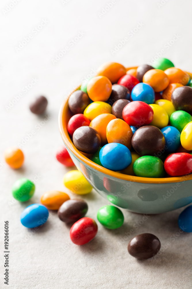 Colorful chocolate buttons in bowl on gray stone background. Colorful chocolate buttons in bowl on gray stone background.