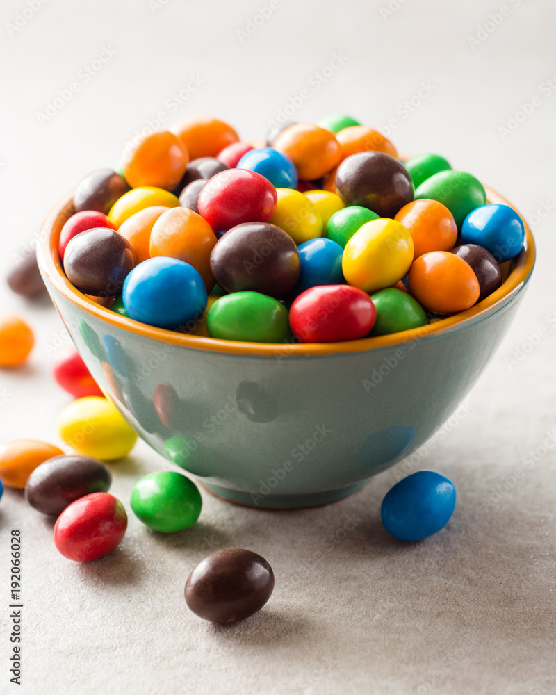 Colorful chocolate buttons in bowl on gray stone background. Colorful chocolate buttons in bowl on gray stone background.