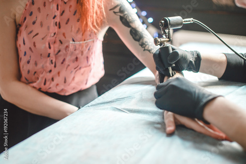 Tattoo is art. Pretty girl getting a tattoo. Image of the bearded tattoo male artist makes a tattoo on a girl hand.