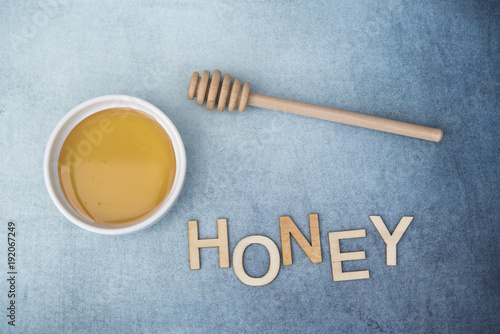 Pot of sweet honey with honey drizzle and the word honey on a blue background 