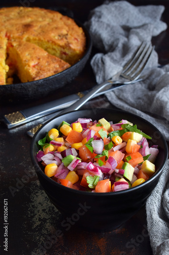 Salad with tomato, red onion, lime, cilantro, corn and cornbread. Mexican food. Copy space.