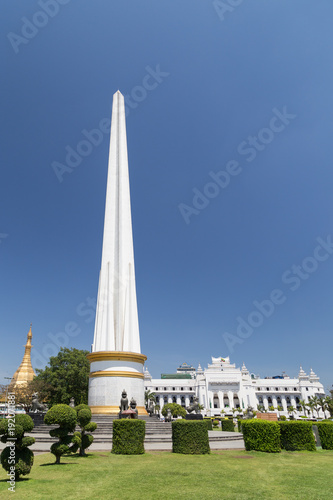 Independence Monument at the Maha Bandula Park on a sunny day. It's a public park in downtown Yangon, Myanmar. Sule Pagoda and the Yangon City Hall are in the background.
