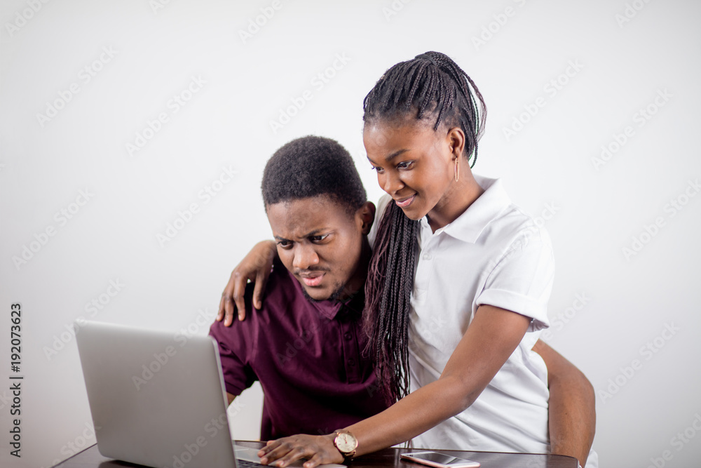 African couple. black girl sitting in front of laptop lookin at screen and laughing