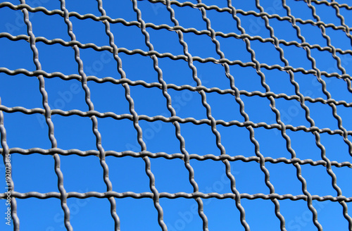 Metal grid against blue sky background texture