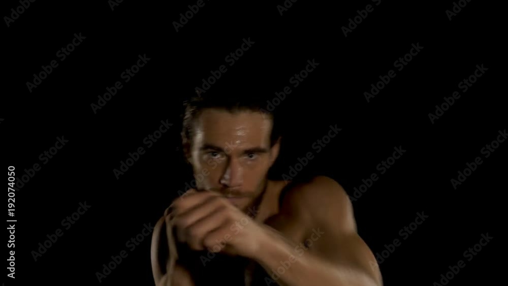 Young kickboxer shadow boxing as exercise to training for the fight. Boxing in the darkness. Young kickboxer shadow boxing as exercise to training for the fight. Boxing in the darkness.