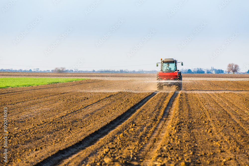 Fototapeta premium Farmer fertilizing arable land with nitrogen, phosphorus, potassium fertilizer