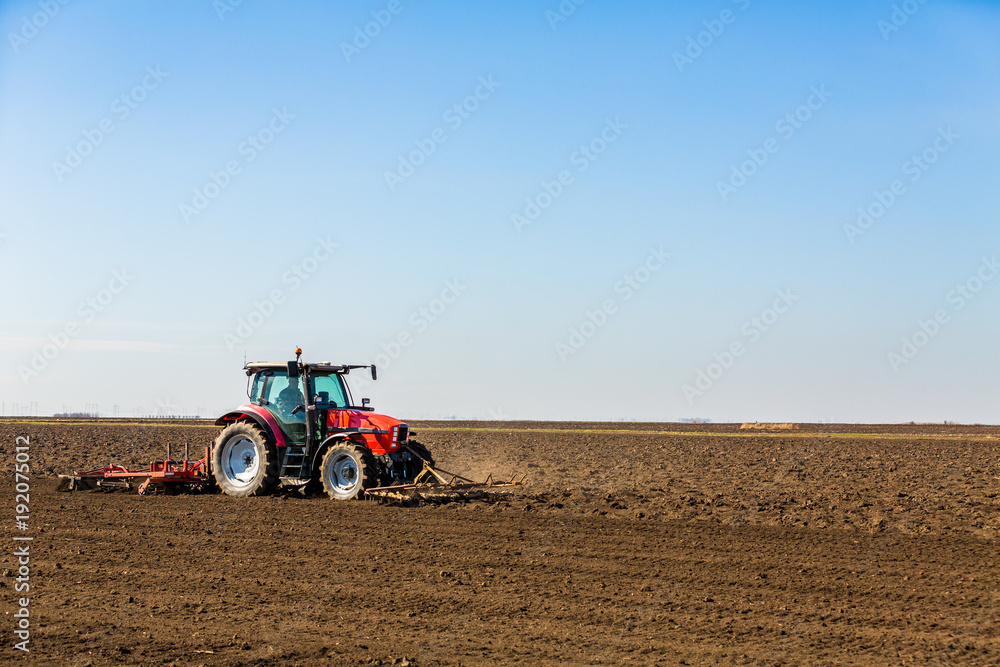 Obraz premium Farmer in tractor preparing land with seedbed cultivator as part of pre seeding activities in early spring season of agricultural works at farmlands.