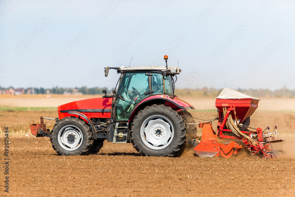 Fototapeta premium Farmer seeding, sowing crops at field. Sowing is the process of planting seeds in the ground as part of the early spring time agricultural activities.
