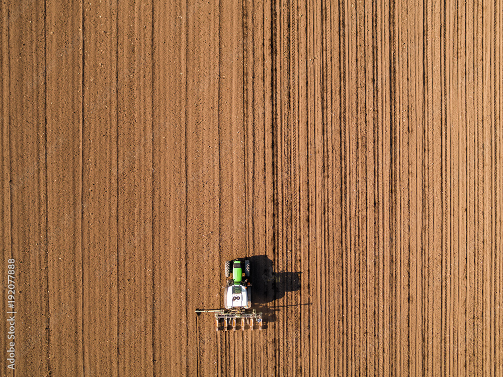 Aerial shot of a farmer seeding, sowing crops at field. Sowing is the process of planting seeds in the ground as part of the early spring time agricultural activities. Aerial shot of a farmer seeding, sowing crops at field. Sowing is the process of planting seeds in the ground as part of the early spring time agricultural activities.