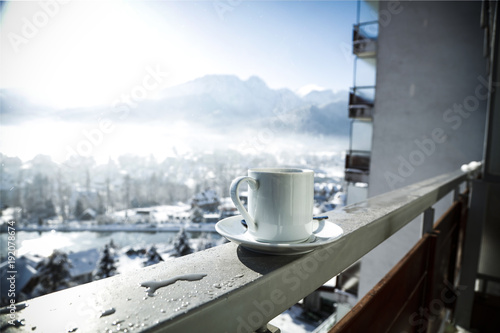 Fototapeta Naklejka Na Ścianę i Meble -  hot coffee on a handrail in a white mug surrounded by beautiful winter mountains