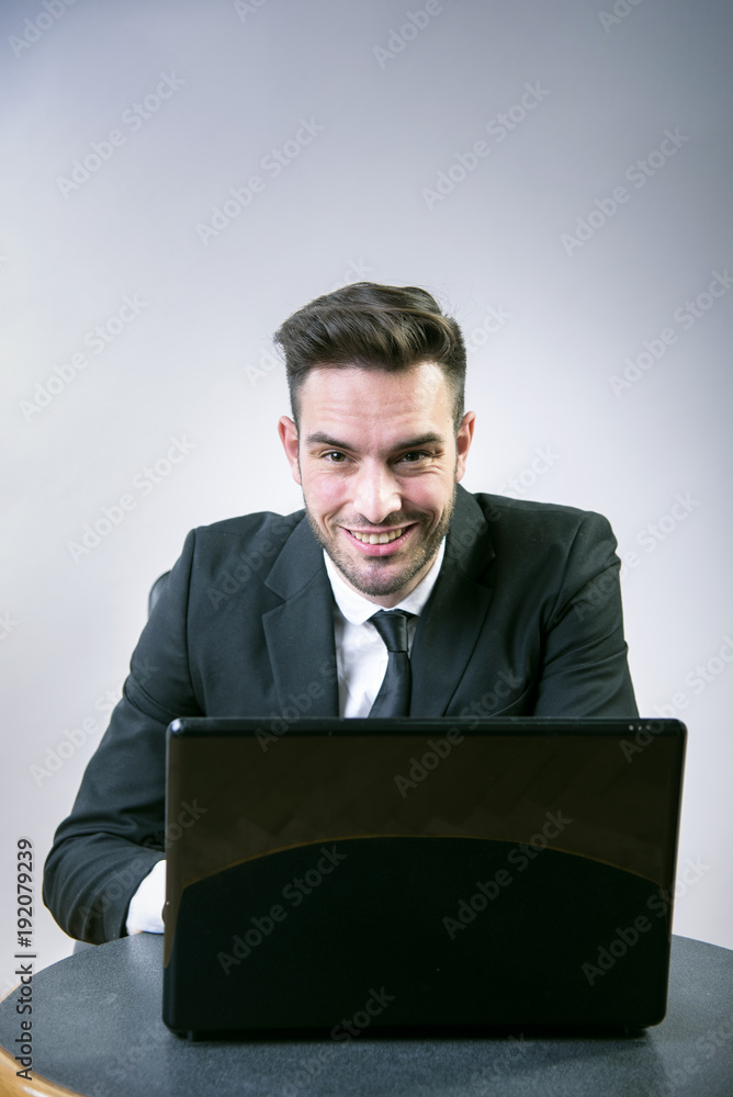 Clever young business man sitting at his desk, working on his laptop