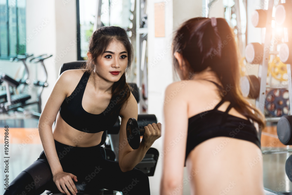 Attractive young woman working out with dumbbells at gym Attractive young woman working out with dumbbells at gym