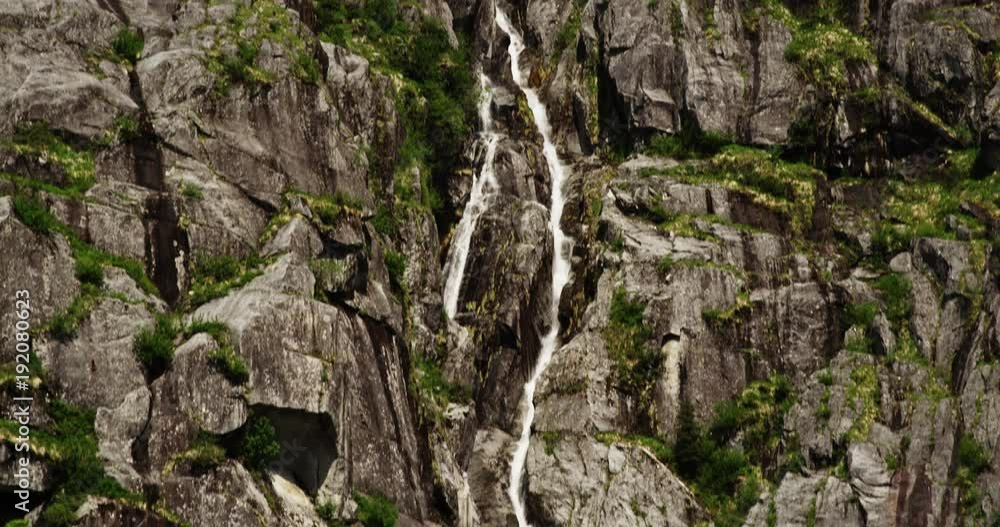 Tilt down, waterfall cascades in slow motion Tilt down, waterfall cascades in slow motion