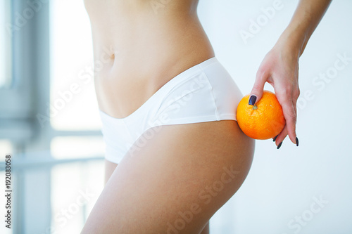 Woman with an orange showing a perfect skin