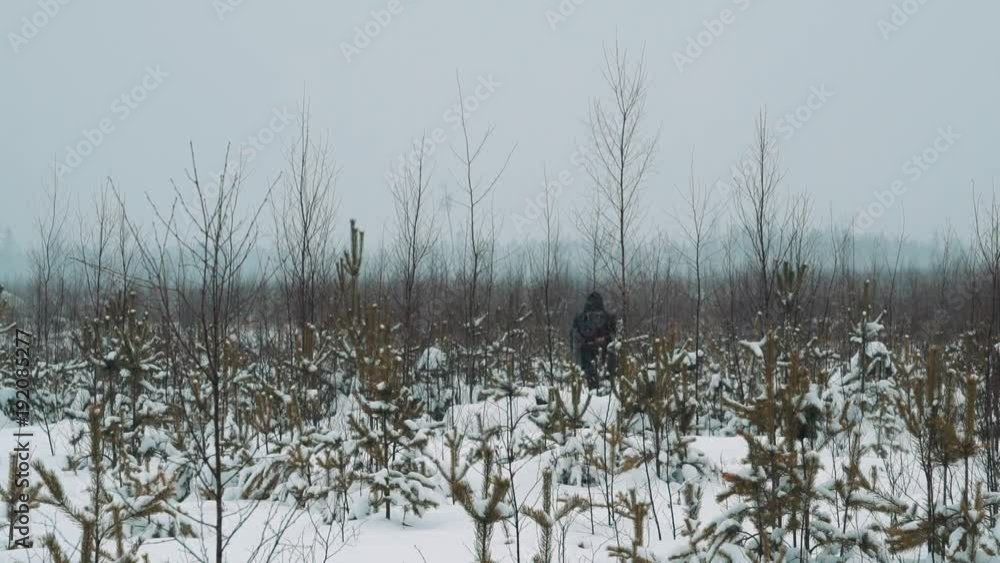 Young guy in warm clothes and backpack walking on snow covered prairie shrubbery on cold cloudy winter day Young guy in warm clothes and backpack walking on snow covered prairie shrubbery on cold cloudy winter day