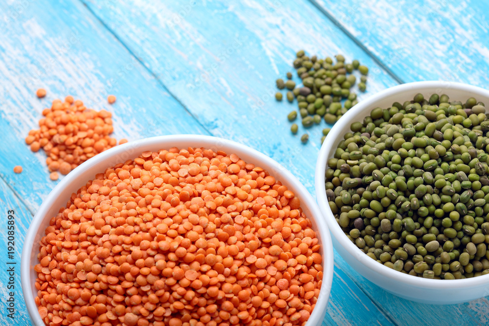 Fototapeta premium Red lentils and green bean or mung bean in bowl on a blue wooden table.Copy space.Top view