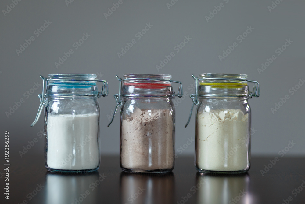 Three glass jars with protein powder, strawberries, banana and chocolate for making milk shakes. Sports and dietary nutrition for athletes and weight loss or muscle mass bodybuilders. Three glass jars with protein powder, strawberries, banana and chocolate for making milk shakes. Sports and dietary nutrition for athletes and weight loss or muscle mass bodybuilders.