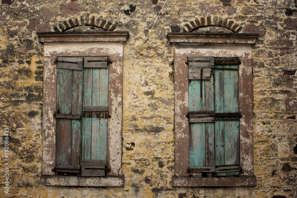 Close up view of old, rusty, closed wooden shutters and stone wa Close up view of old, rusty, closed wooden shutters and stone wa