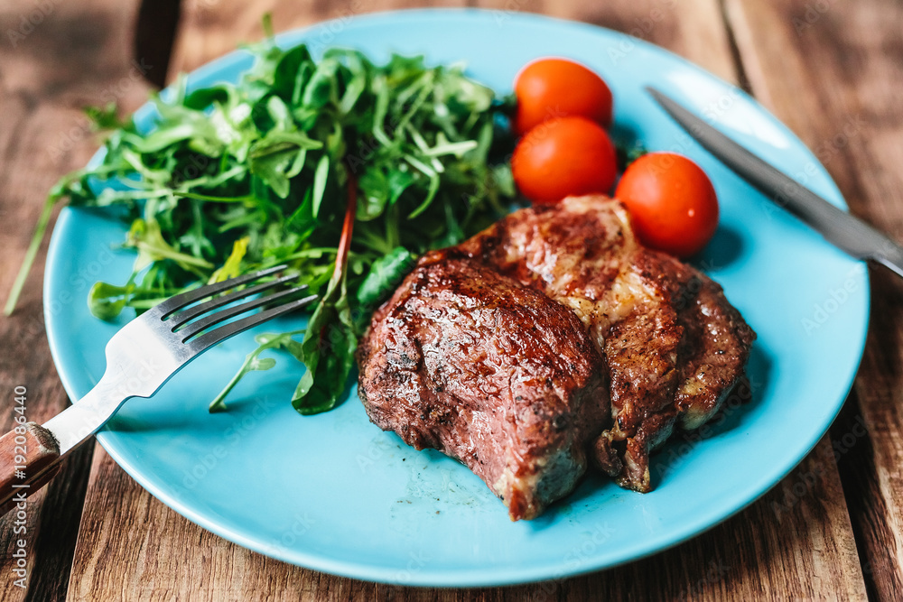 delicious steak with tomatoes and salad on a wooden background delicious steak with tomatoes and salad on a wooden background