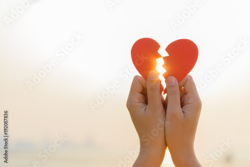 Bilde på lerret Woman hand holding broken paper red heart on sunset