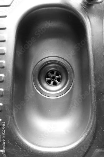 Dirty and scratched domestic kitchen sink and plug hole in black and white