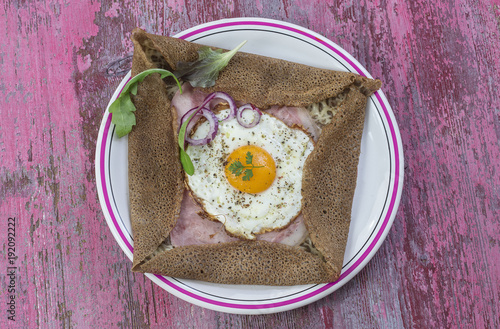 french Buckwheat crepe galette with ham and egg for tasty healthy lunch on a pink wooden background photo