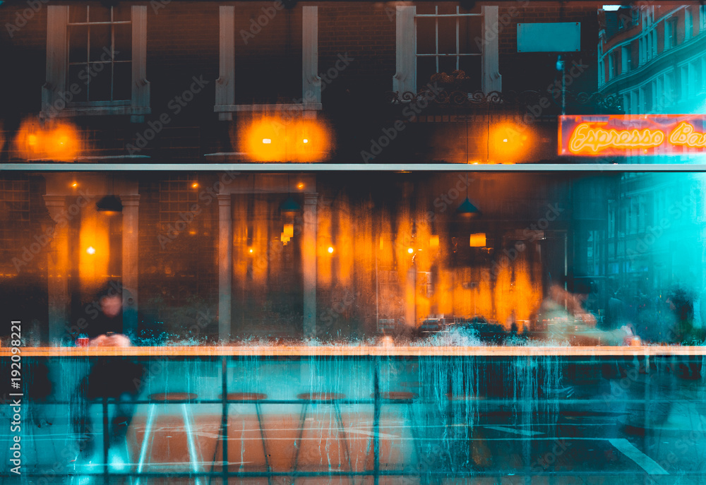 Fototapeta premium blurred glass facade of espresso bar in winter with orange lights inside and cold blue colors outside the window