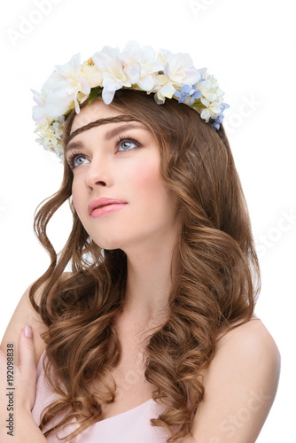 young woman with curly hair in white floral wreath looking up isolated on white