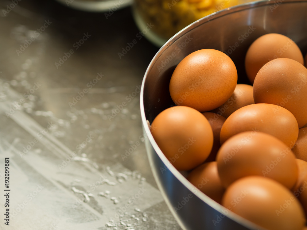 Close up of dozen of chicken eggs with brown eggshells in a prepared bowel on wooden table in kitchen or pastry, for cooking or baking pastry or Easter day party Close up of dozen of chicken eggs with brown eggshells in a prepared bowel on wooden table in kitchen or pastry, for cooking or baking pastry or Easter day party