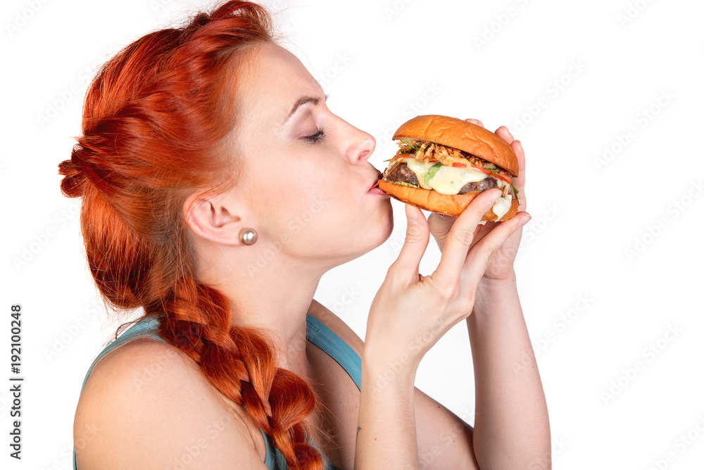 young woman with appetite eating a hamburger in profile