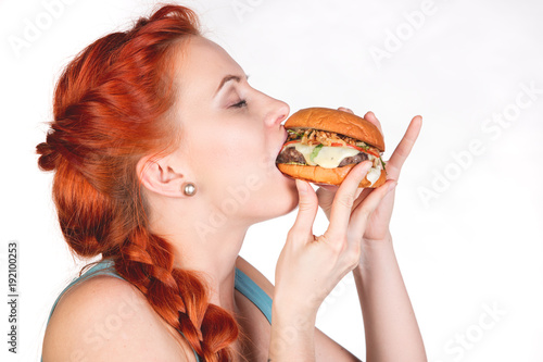 young woman eating  hamburger in profile