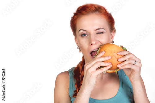 young woman trying to bite hamburger